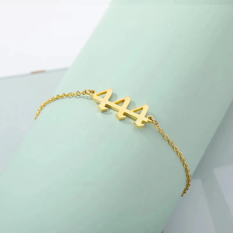 Gold bracelet with 444 on a light green background