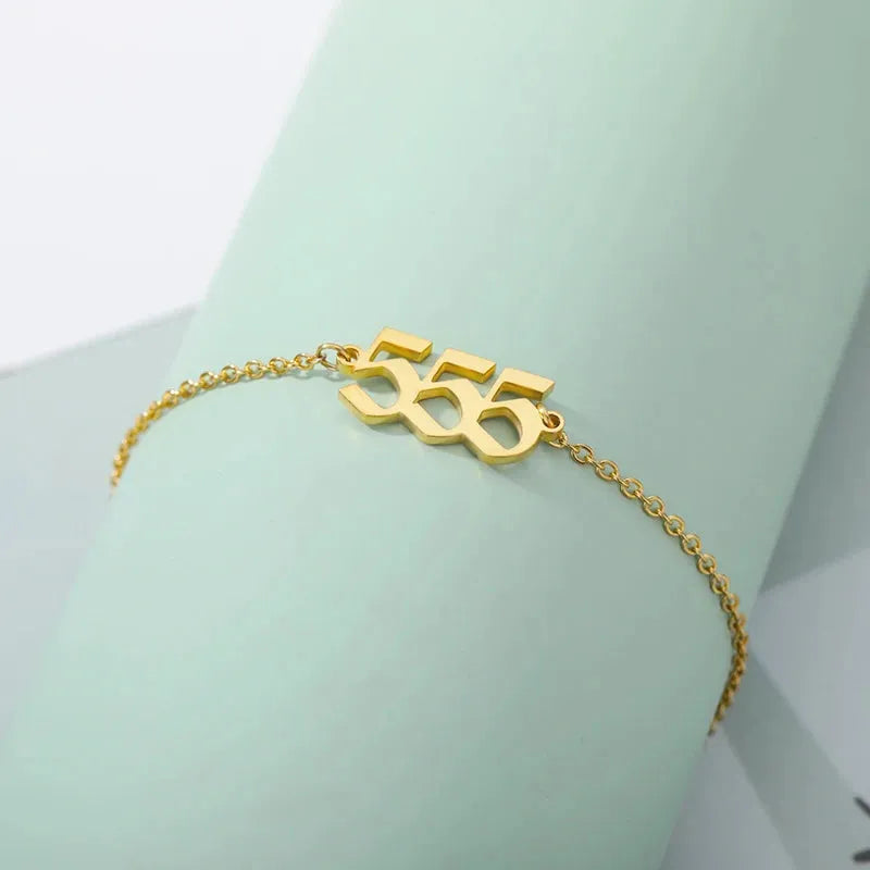 Gold bracelet with numbers on a light green background 555