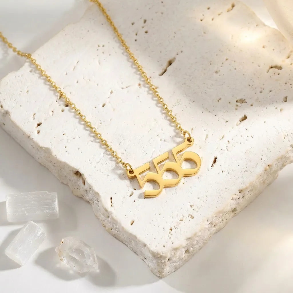 Gold necklace with the number '555' on a white stone surface