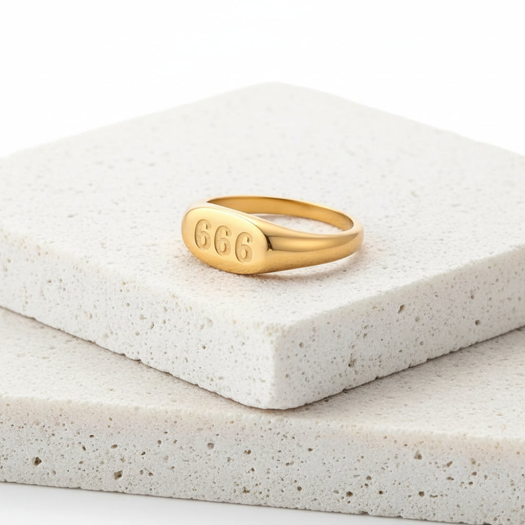 Gold ring with '666' engraving on a white background
