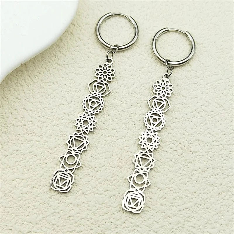 Silver chakra earrings vertical 7 signs with intricate designs on a textured beige surface