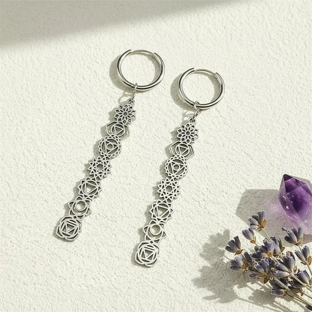 Silver chakra earrings vertical 7 signs with intricate designs on a textured beige surface
