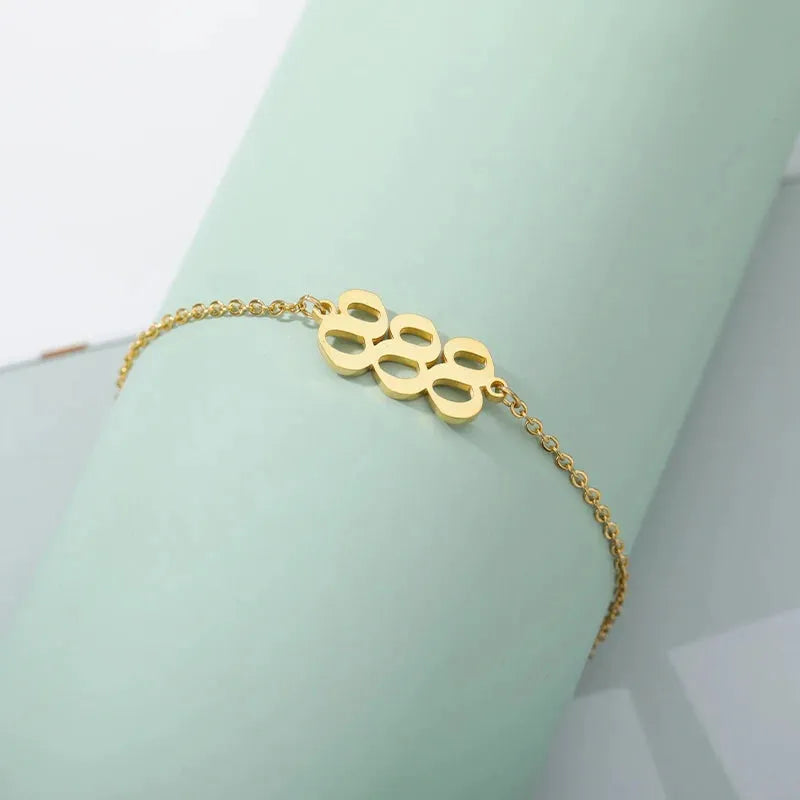 888 Gold bracelet with paw print design on a light green background