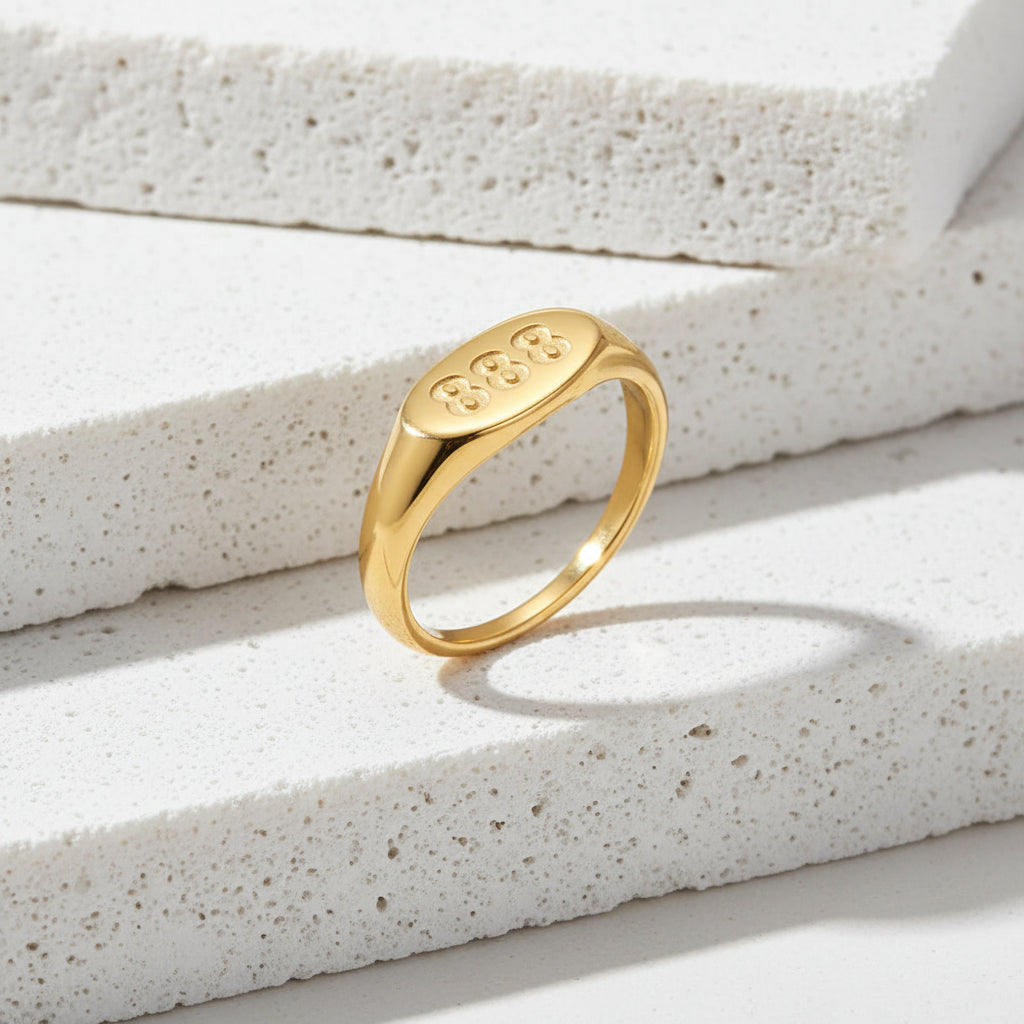 Gold ring with '888' engraving on a white background