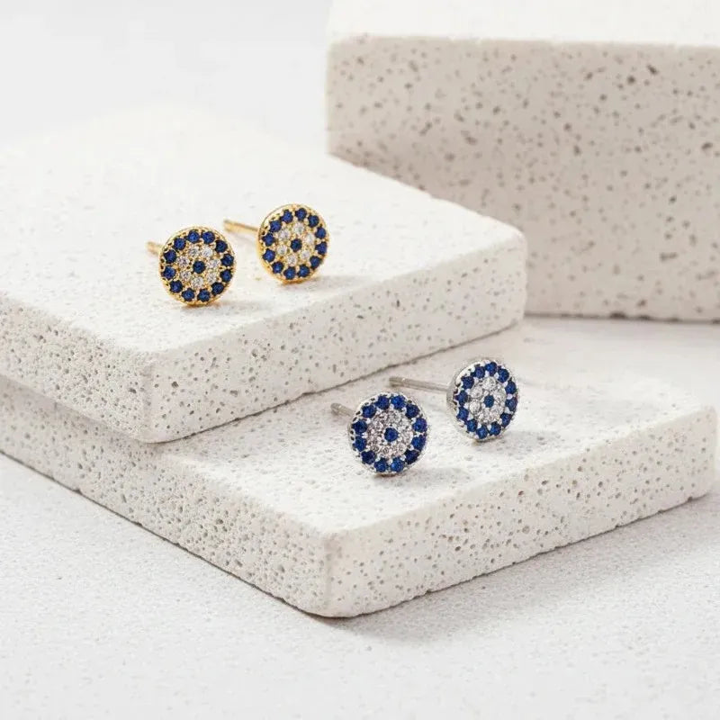 Pair of blue and gold earrings on a textured white surface