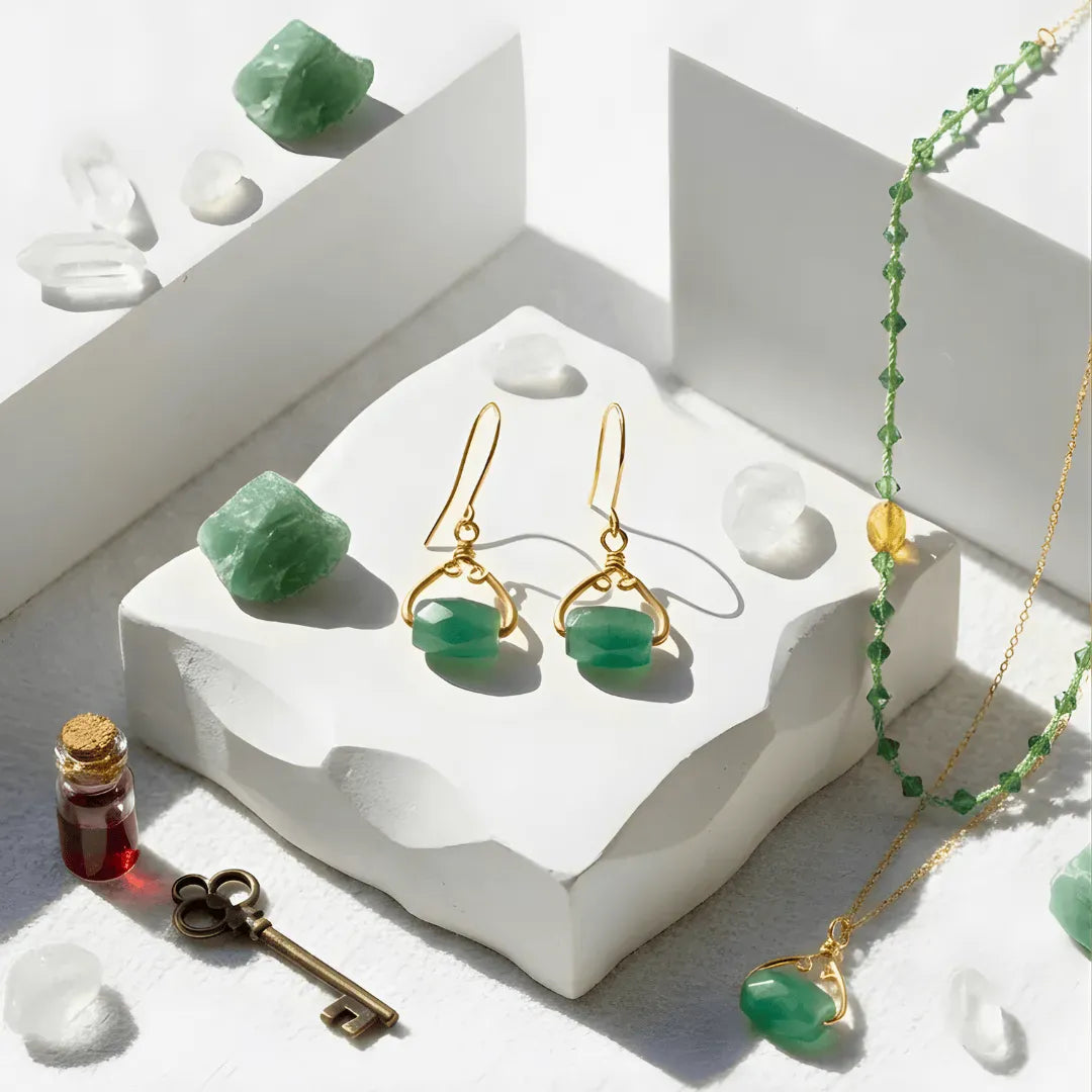 Green gemstone jewelry set including earrings and necklace on a white stone surface with crystals and a key.