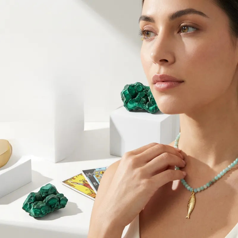 Woman wearing a turquoise necklace with a gold pendant, surrounded by  