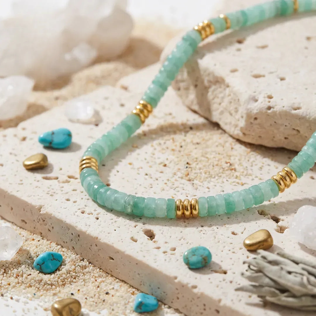 Turquoise beaded bracelet with gold accents on a sandy surface with turquoise stones.