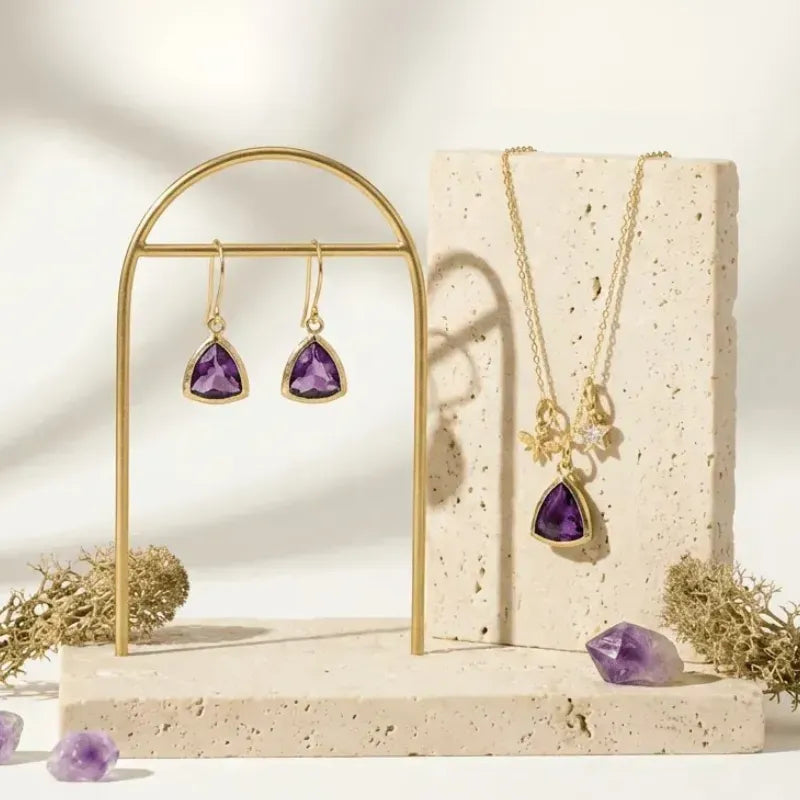 Jewelry set with purple teardrop-shaped gemstones on a decorative stand.