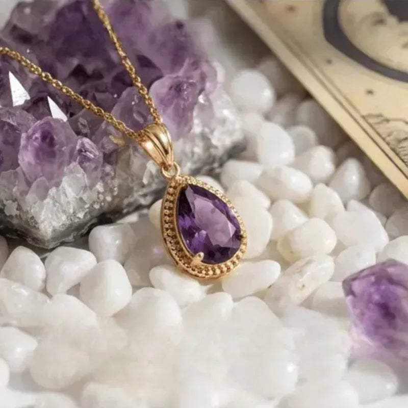 Amethyst pendant necklace on a surface with amethyst crystals