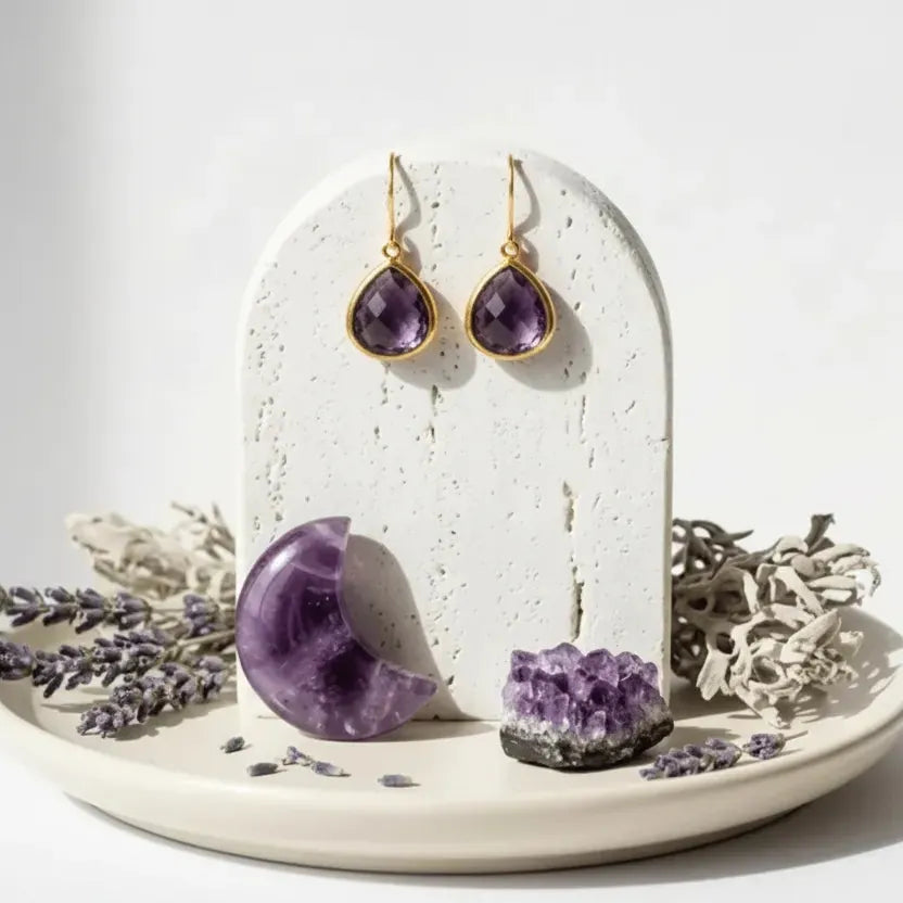 Amethyst earrings on a white stand with amethyst crystal and lavender flowers on a white background