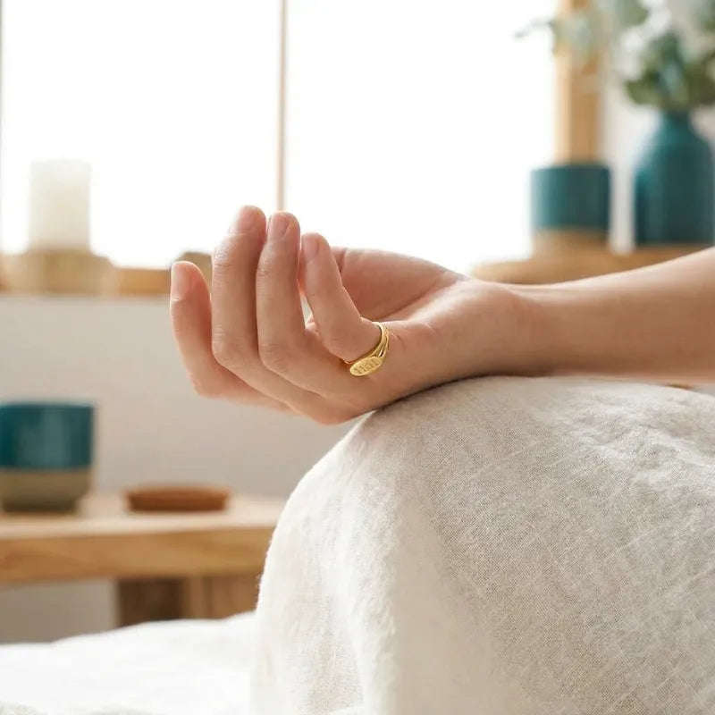 Hand with a gold ring on a white surface with a blurred background
