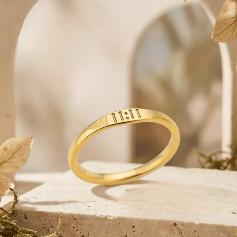 Gold ring with engraved text on a natural stone surface