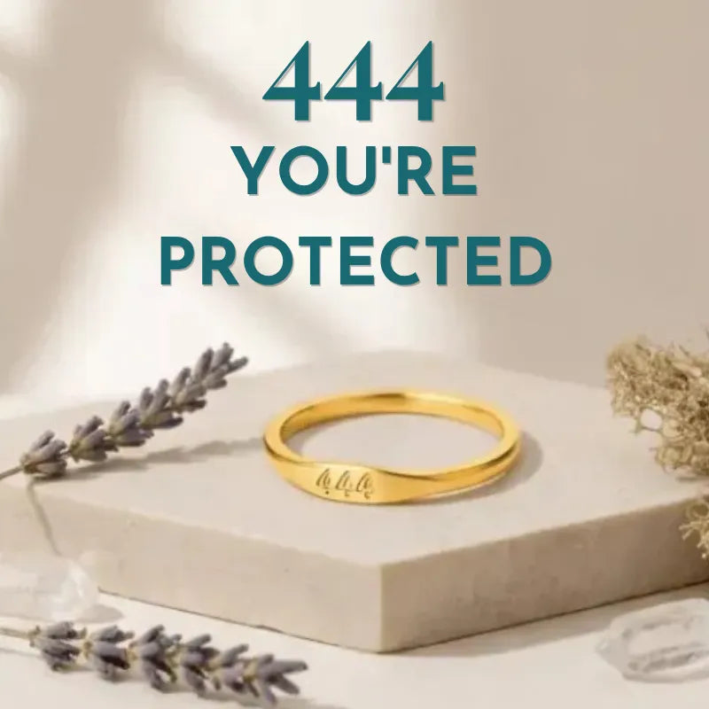 Gold ring on a beige stand with lavender and gold leaves, text '444 YOU'RE PROTECTED' in teal.