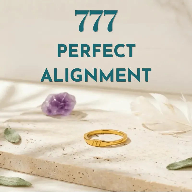 Gold ring on a stone surface with a purple crystal and green leaf, labeled '777 Perfect Alignment'.