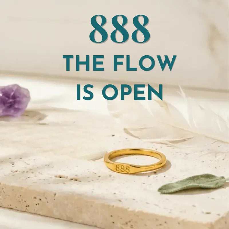 Gold ring with '888' on a stone surface with text 'THE FLOW IS OPEN'.