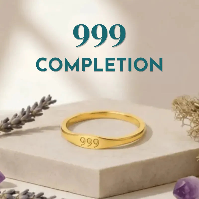 Gold ring with '999' engraving on a beige surface with decorative elements.