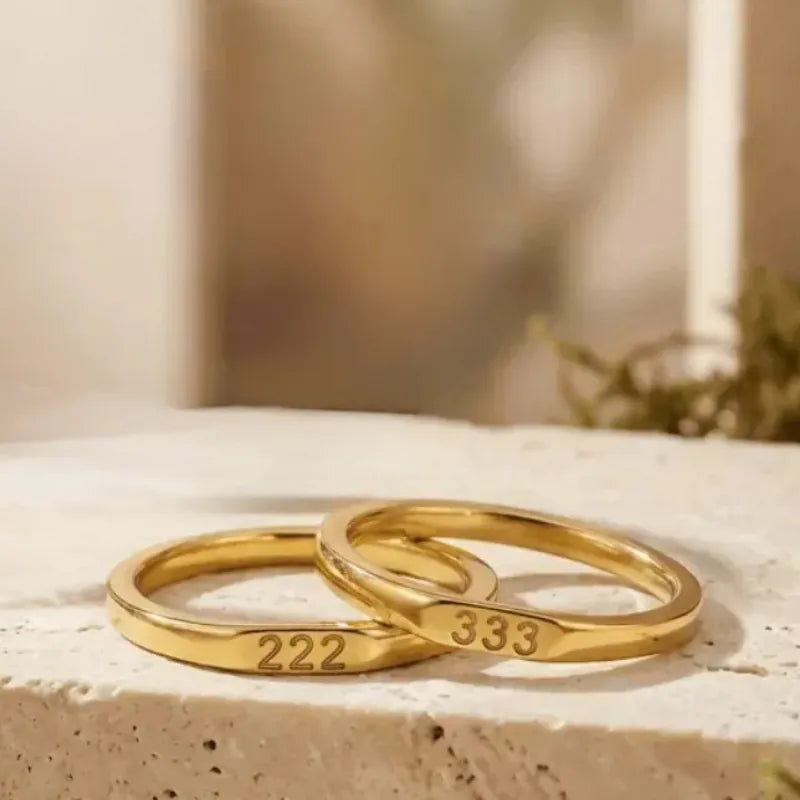 Two gold rings with engraved numbers on a textured surface