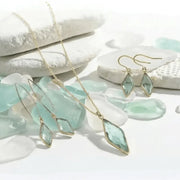 Jewelry set with pendant necklace and earrings on a white stone background