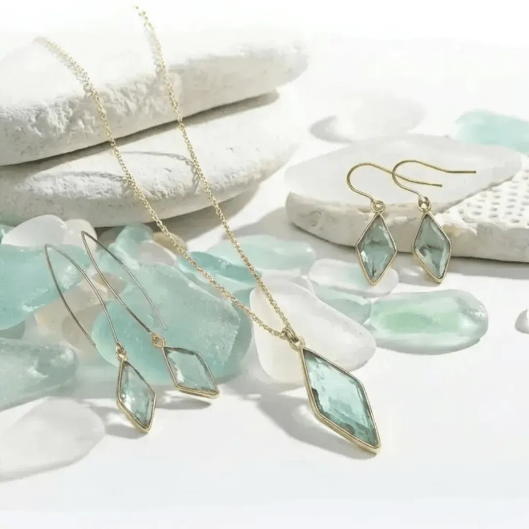 Jewelry set with pendant necklace and earrings on a white stone background