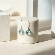 Aqua blue mini drop earrings in gold on display, March birthstone ocean jewelry
