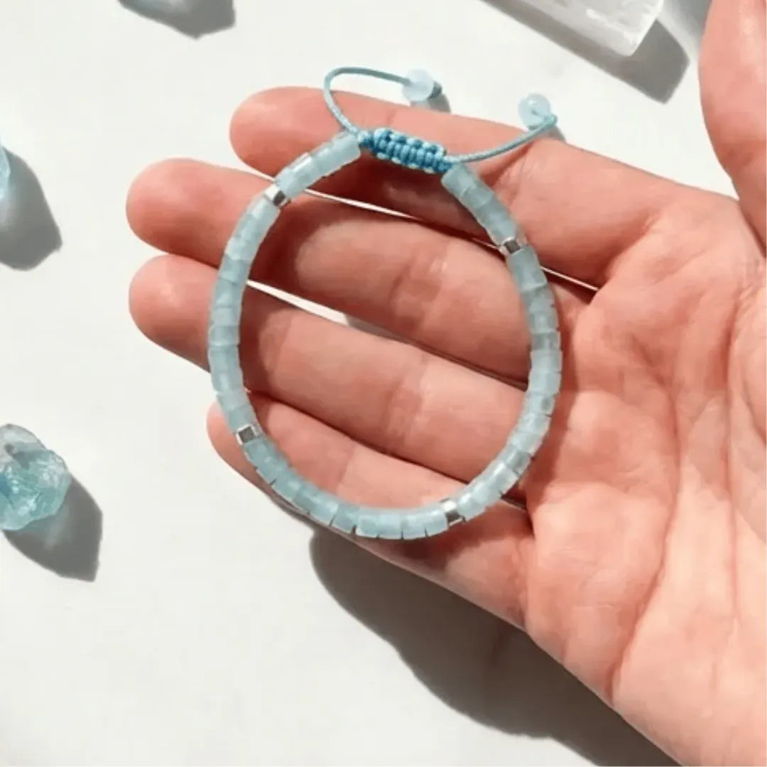 Light blue beaded bracelet on a hand against a white background
