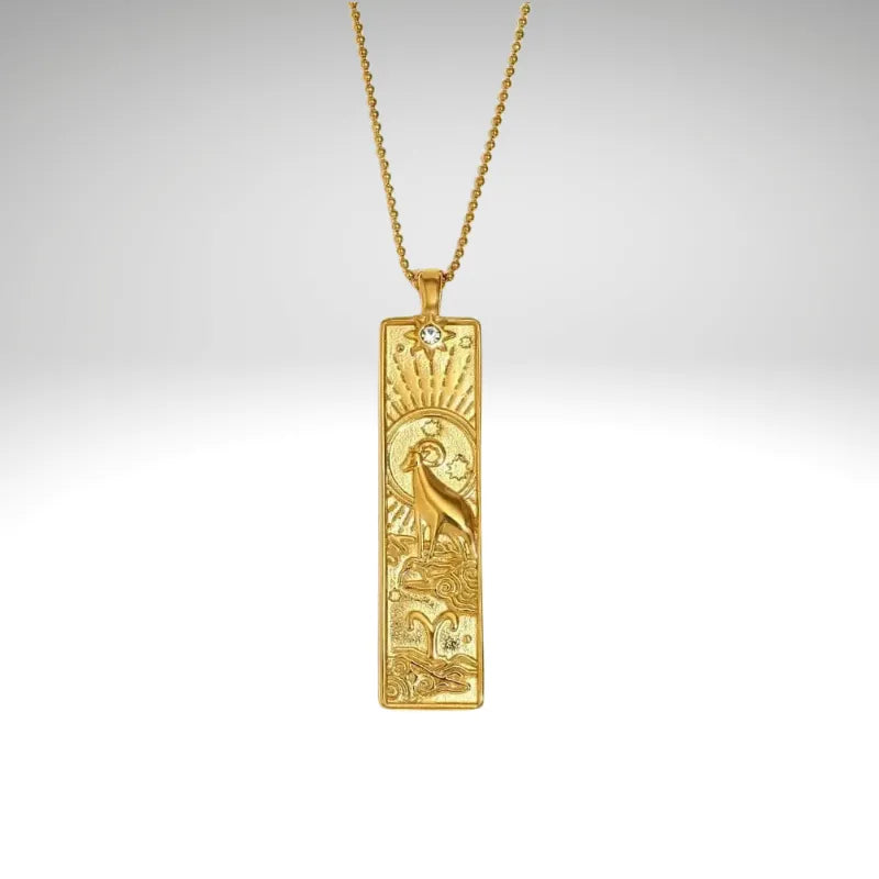 Gold pendant necklace with intricate design on a gray background