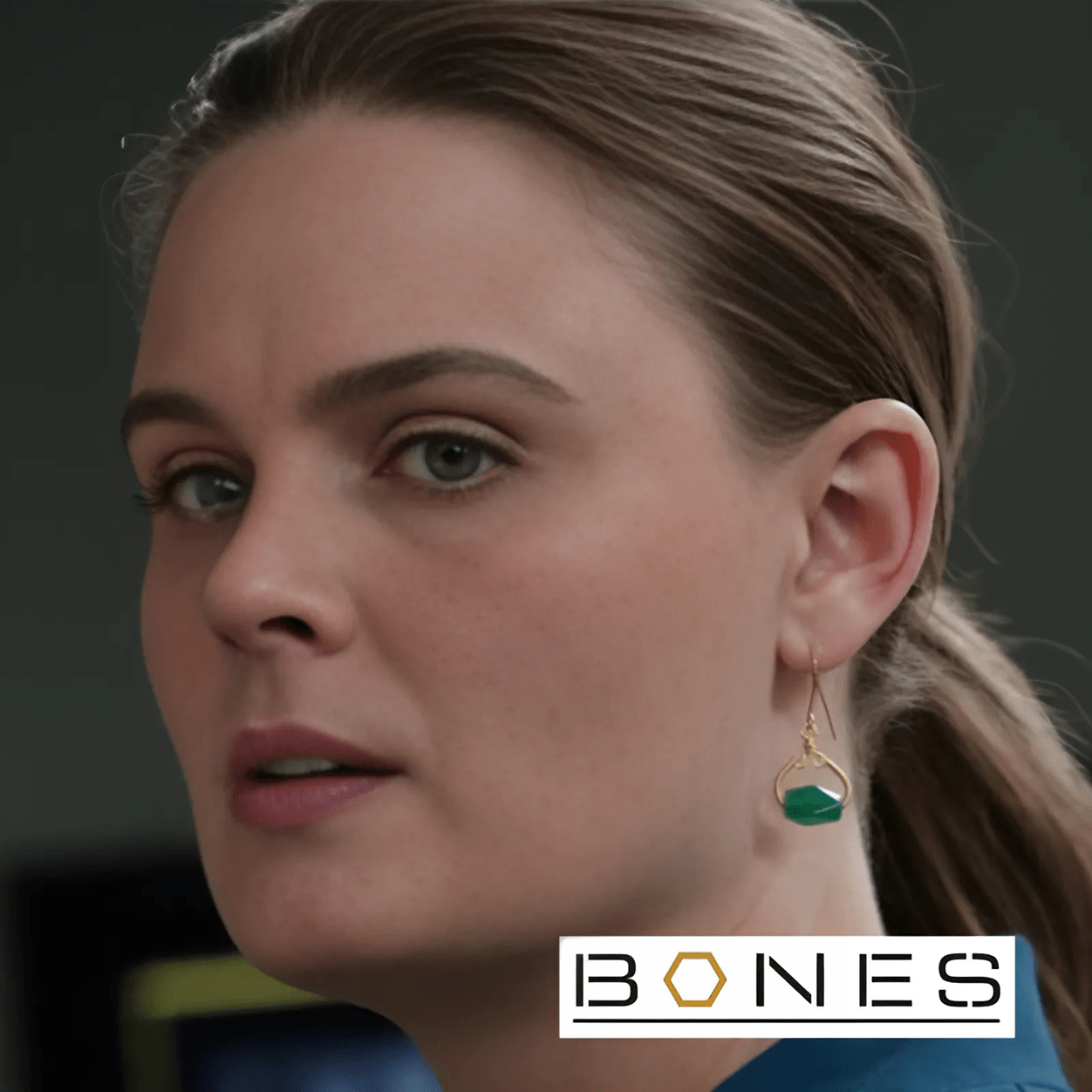 Close-up of a woman wearing earrings with 'BONES' logo in the corner