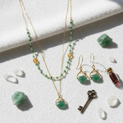 As Seen On Bones and The Vampire Diaries Jewelry set with necklace, earrings, and key on a white surface with green stones and a small bottle.
