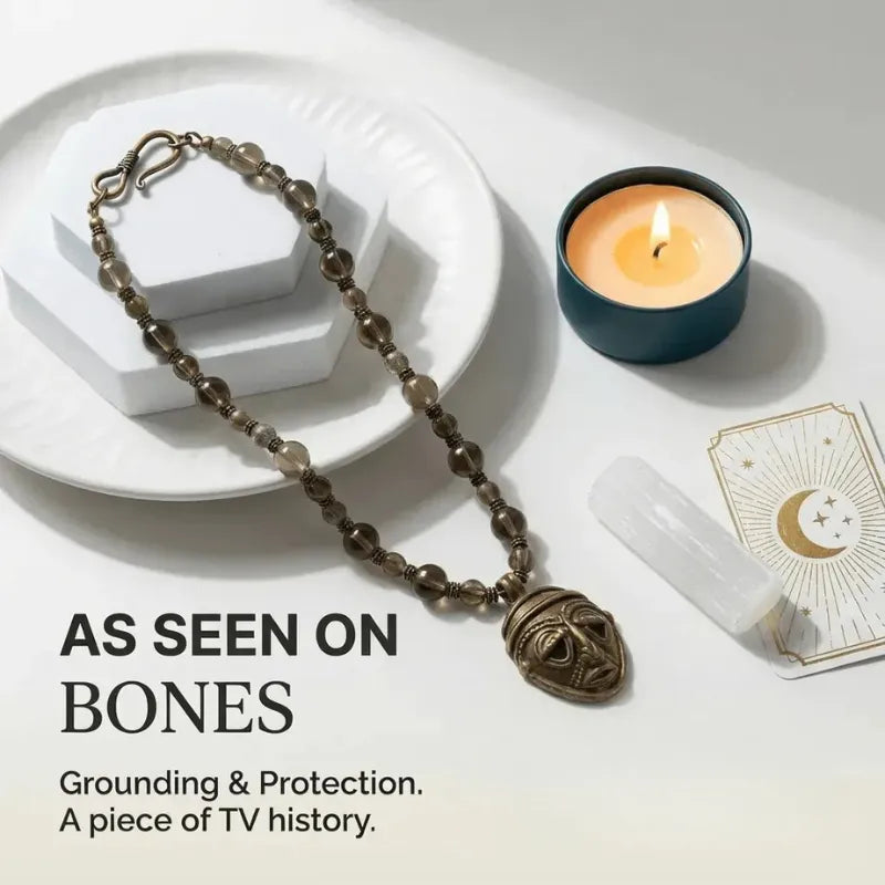Necklace with pendant on a white surface with a candle and card, labeled 'As seen on Bones'.