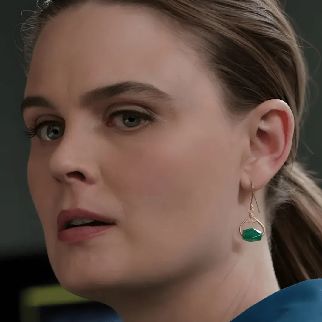 Close-up of a Dr Temperance on Bones wearing a gold earring with a green gemstone.