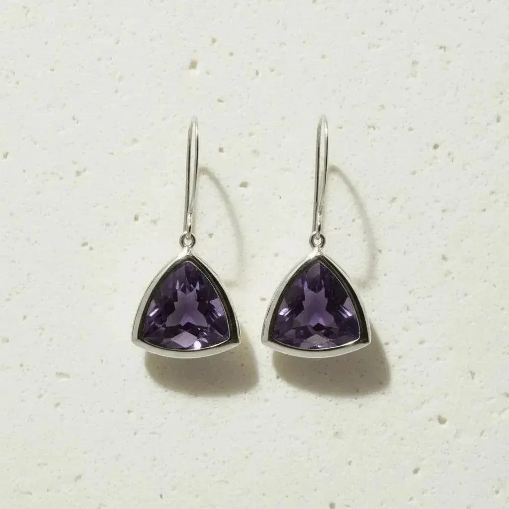 Trillion-shaped purple gemstone earrings on a light background