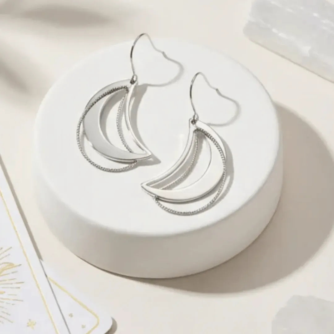 Silver hoop earrings on a white jewelry dish with a soft beige background