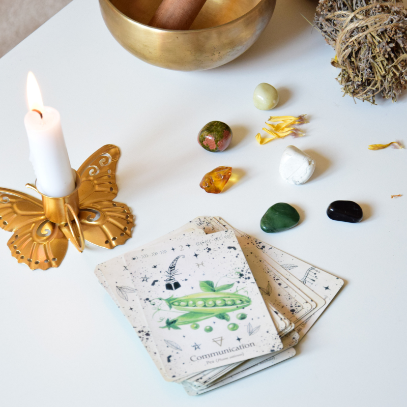 Tarot cards with crystals, a candle, and a singing bowl on a white surface