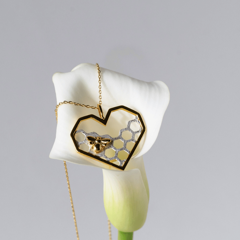 Heart-shaped pendant with honeycomb design on a white flower against a gray background