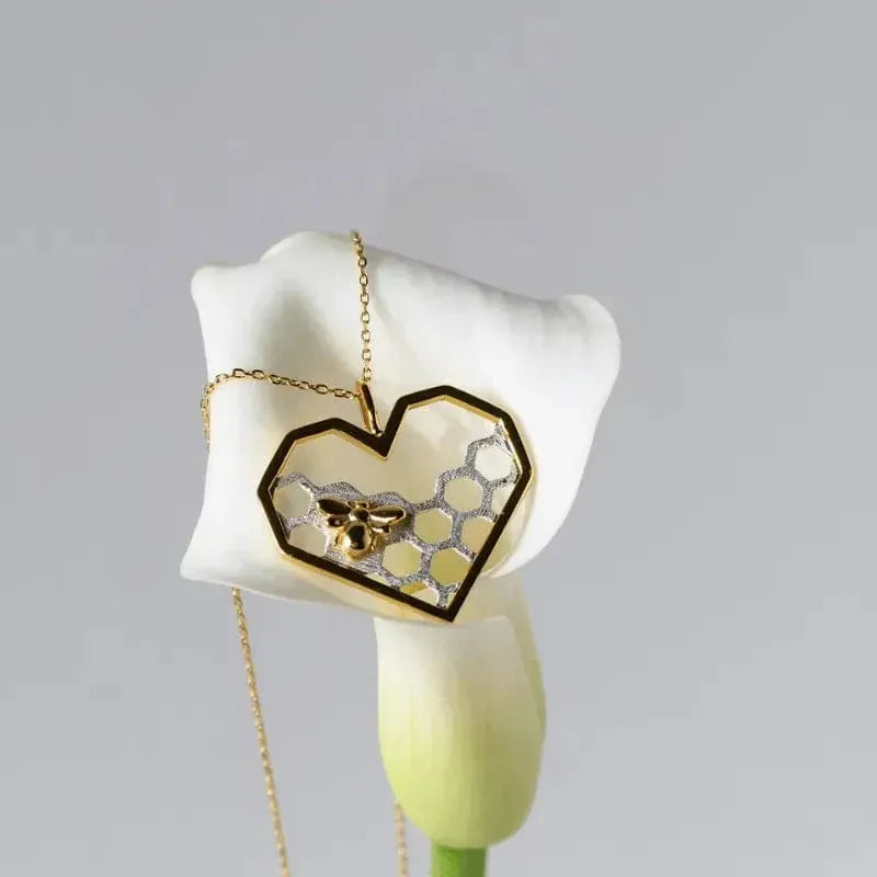Heart-shaped pendant with honeycomb design on a white flower against a gray background