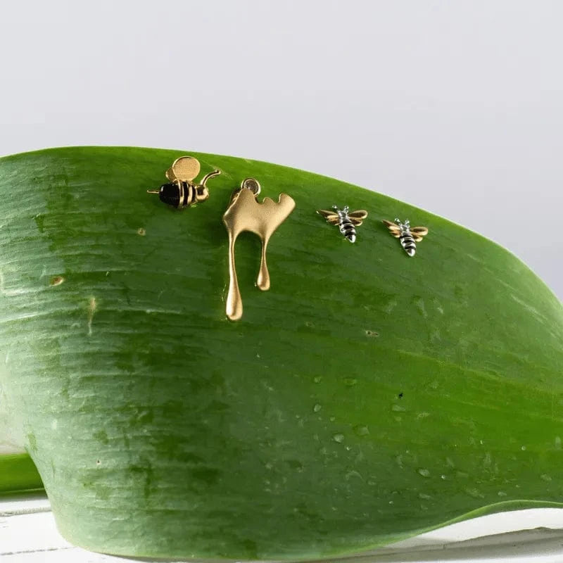 Gold bee and honeycomb earrings on a green leaf