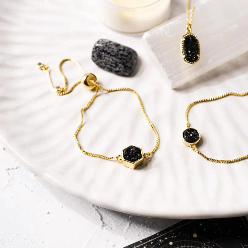 Gold bracelets with black stones on a marble surface