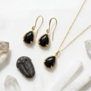 Gold jewelry set with black stones on a white background