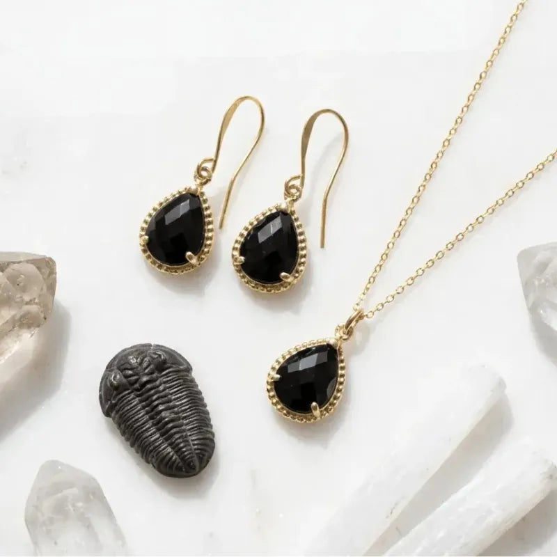 Gold jewelry set with black stones on a white background