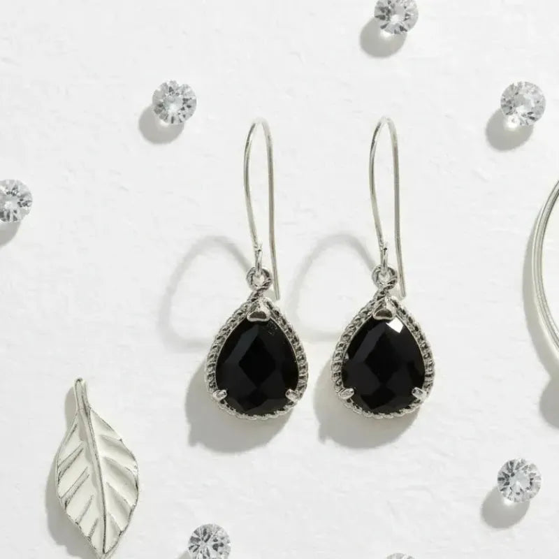 Black teardrop earrings with silver hooks on a light gray background