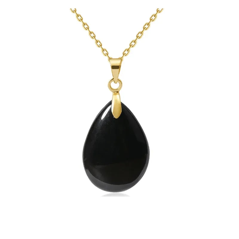 Gold necklace with a black teardrop pendant on a white background