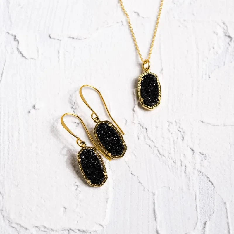 Black druzy earrings and necklace on a white textured background