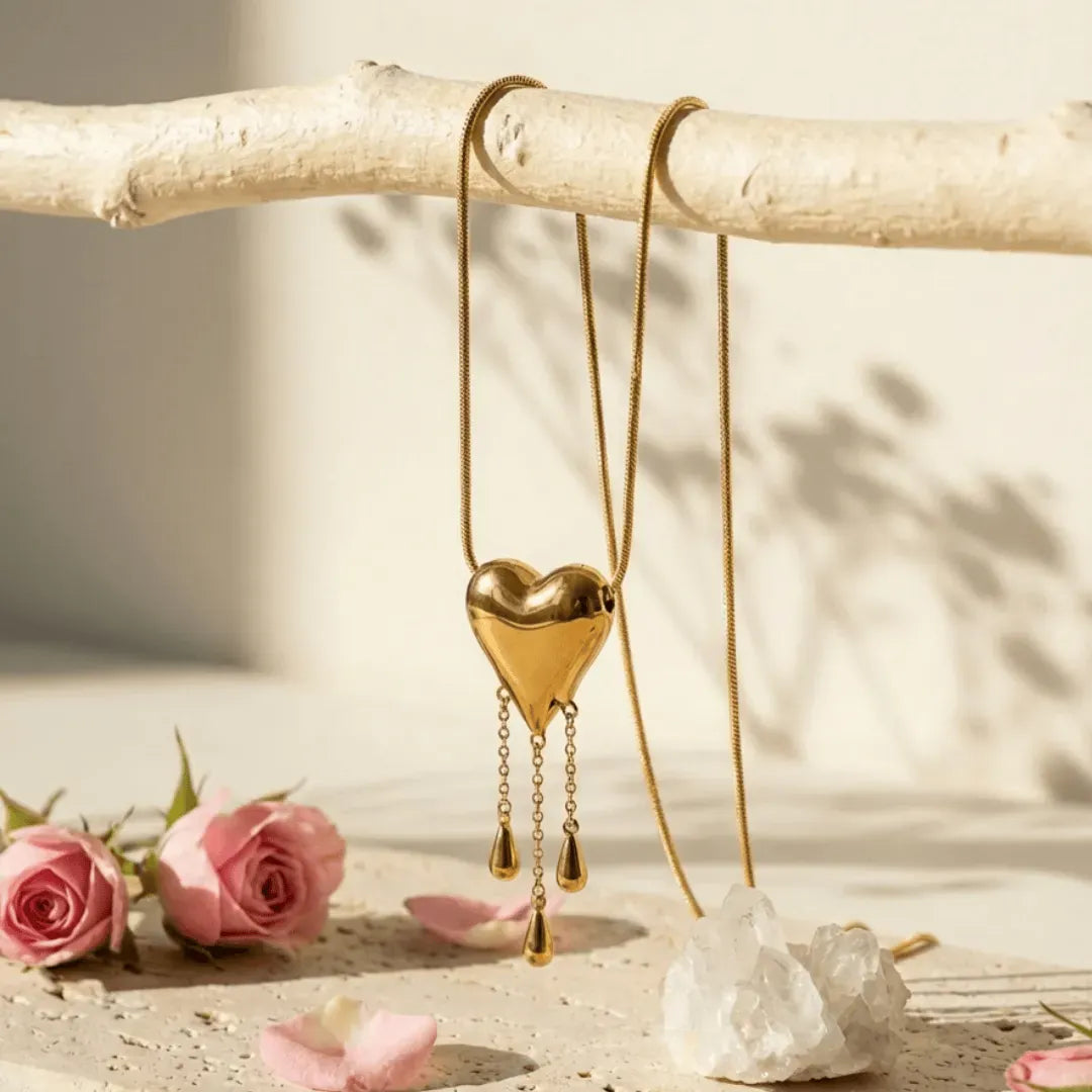 Gold heart-shaped pendant necklace on a branch with pink roses and crystals.
