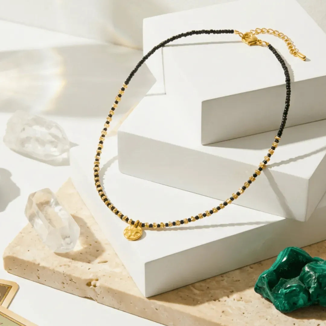 Necklace with gold and black beads on a white surface