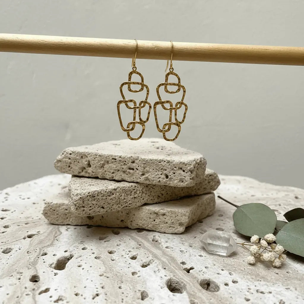 Gold chain earrings on a stone surface with a neutral background