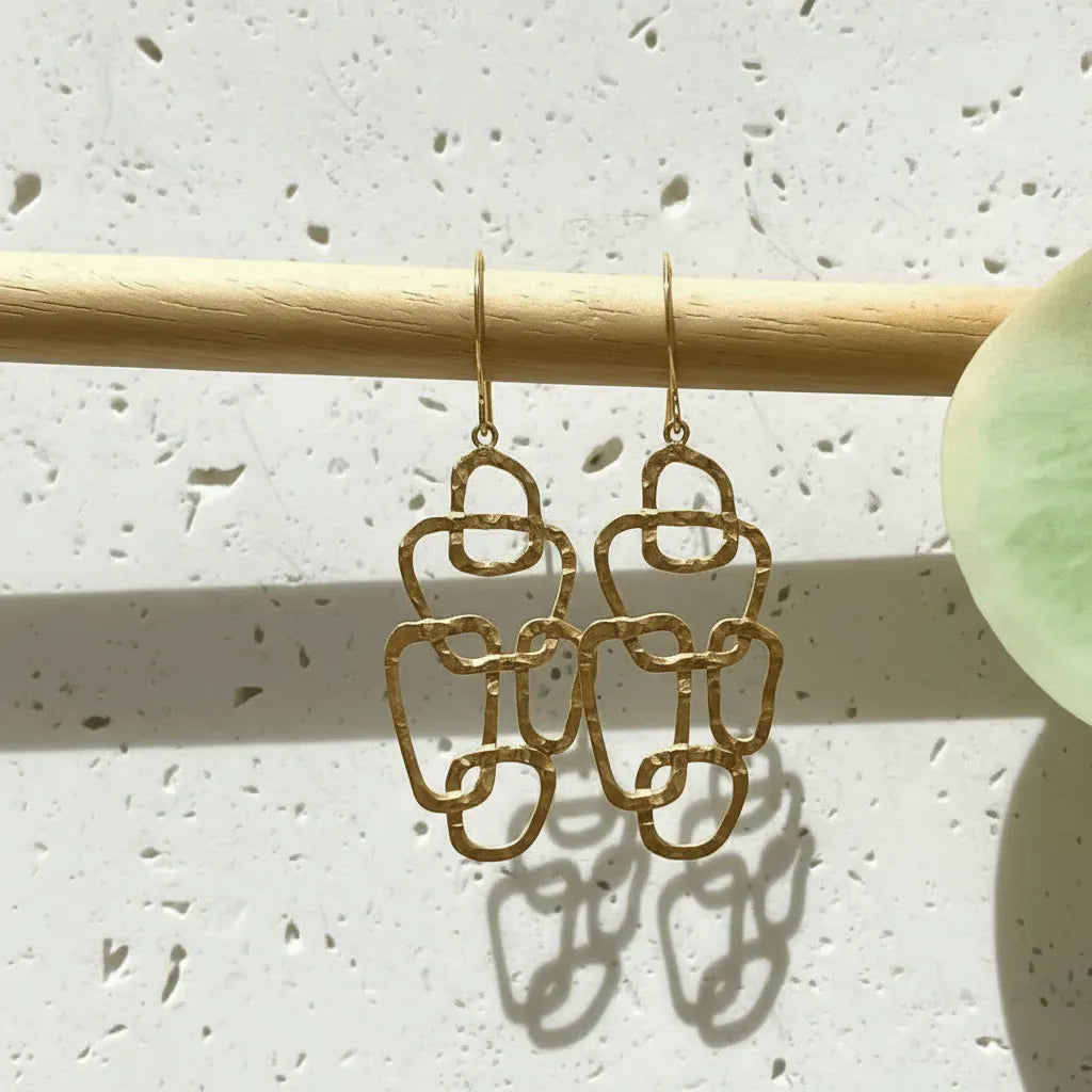 Gold earrings on a wooden stick against a light background