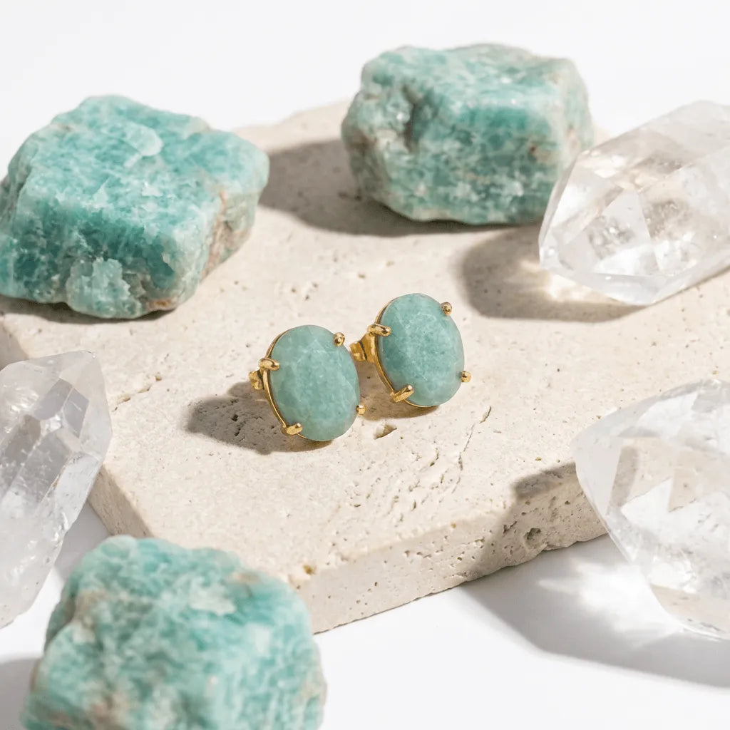 Teal earrings with gold accents on a surface with natural stones