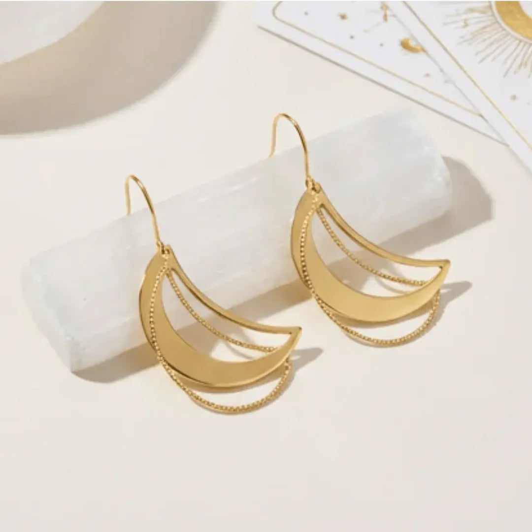 Gold crescent moon earrings on a white surface