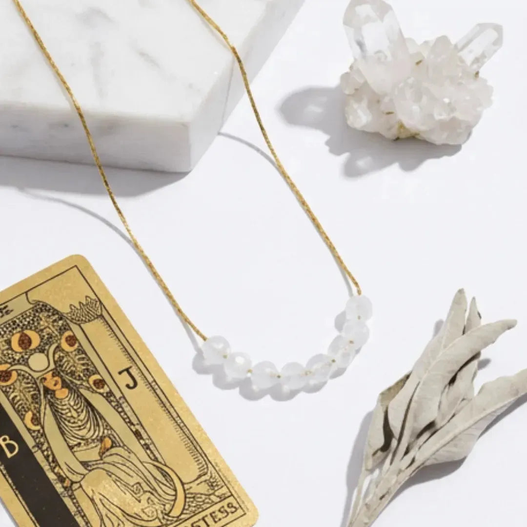 Necklace with white beads on a tarot card and crystal background